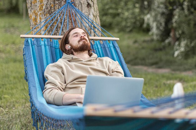 Homme relaxant dans la nature tout en étant assis dans un hamac