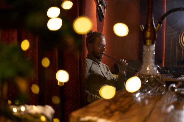 Homme relaxant en vapotant d'un narguilé dans un bar