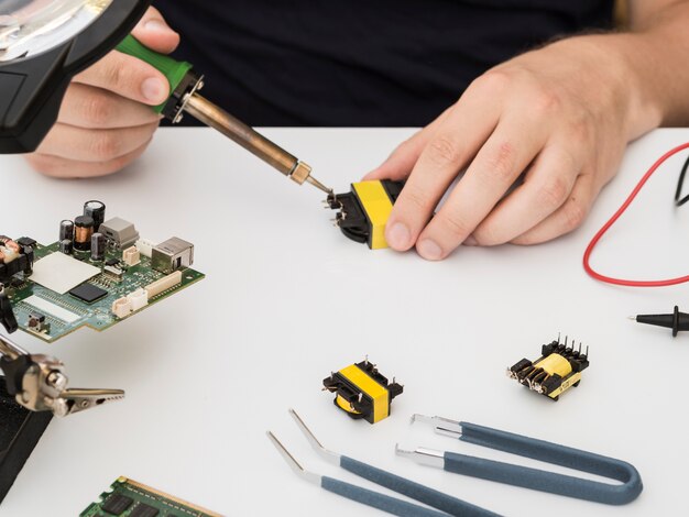 Homme réparant un connecteur à l'aide du fer à souder