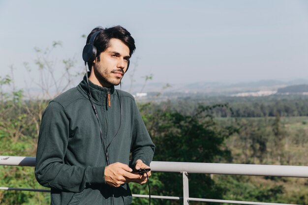 Homme rêveur dans les écouteurs avec téléphone