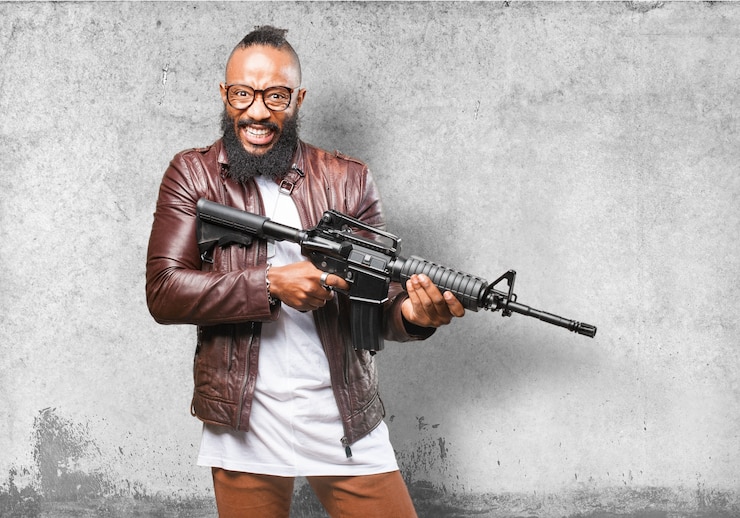 Photo gratuit l&#39;homme en riant tout en tenant une arme automatique