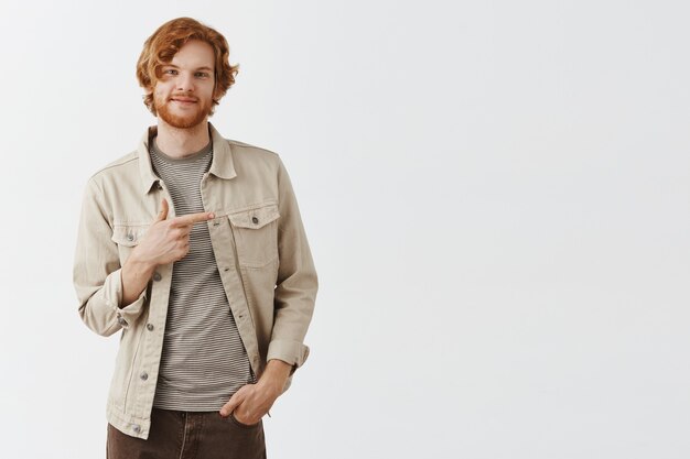 Homme rousse barbu confiant posant contre le mur blanc