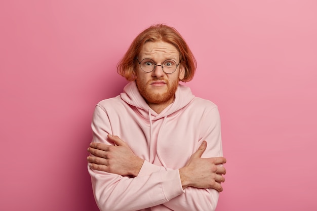 Un homme rousse bouleversé croise les bras sur le corps, tente de se réchauffer