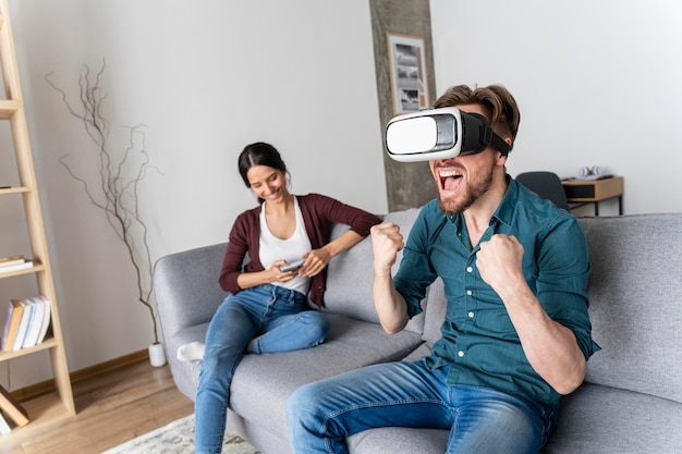 L'homme s'amuse à la maison sur le canapé avec un casque de réalité virtuelle