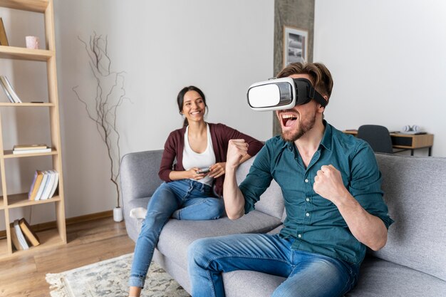 L'homme s'amuse à la maison sur le canapé avec un casque de réalité virtuelle