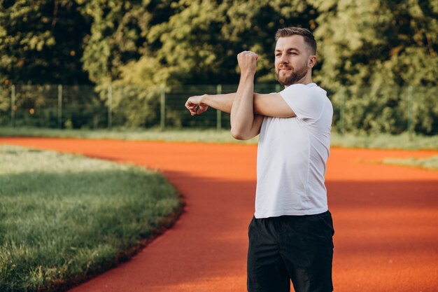 Homme s'étirant avant l'entraînement au stade