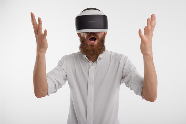 Homme s'exclamant et levant les mains étant fasciné et choqué, portant un casque de réalité virtuelle