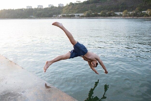 Homme sautant dans l'eau plein coup