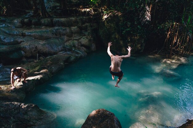Homme sautant dans un étang naturel
