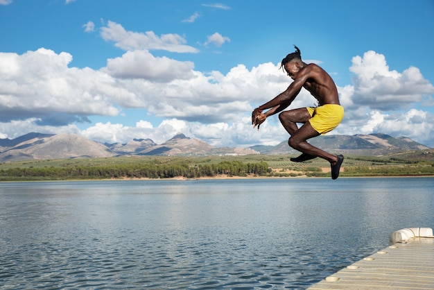 Photo gratuite homme sautant dans le lac plein coup