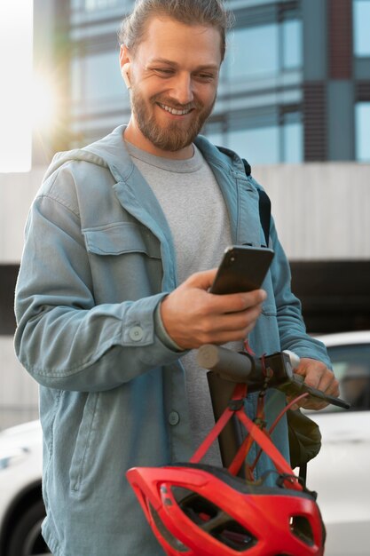 Photo gratuite homme avec scooter regardant son téléphone