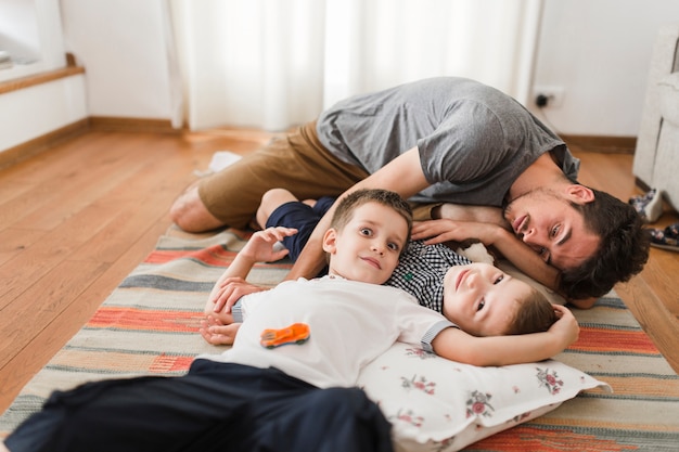 Homme se détendre avec ses deux fils sur le lit