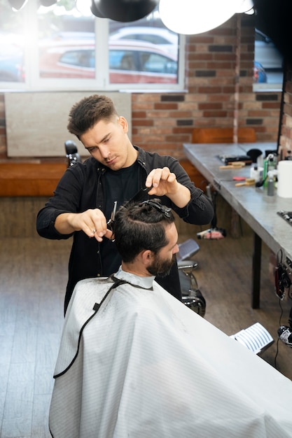 Photo gratuite homme se faisant couper les cheveux au salon coup moyen