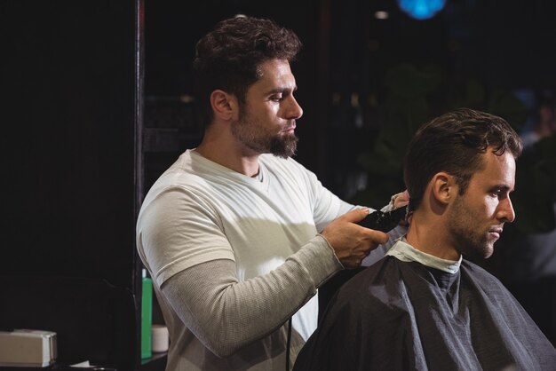 L'homme se fait couper les cheveux avec une tondeuse