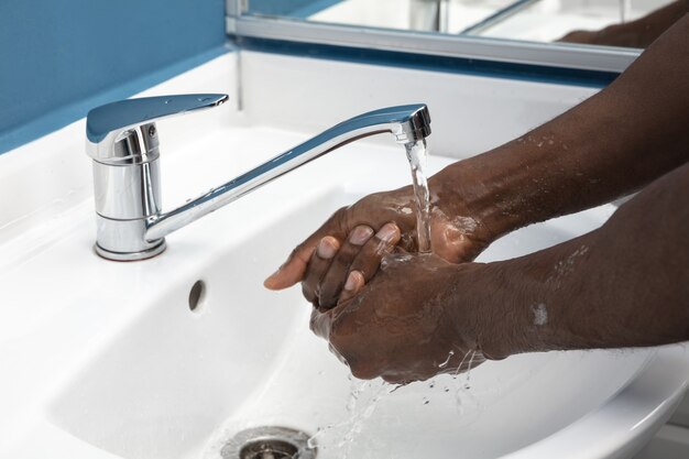 Homme se lavant soigneusement les mains avec du savon et du désinfectant, gros plan.