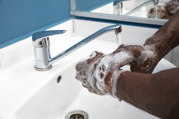 L'homme se lave soigneusement les mains dans la salle de bain close up prévention de l'infection