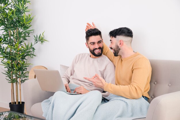 Homme se moquer avec son petit ami à l&#39;aide d&#39;un ordinateur portable à la maison