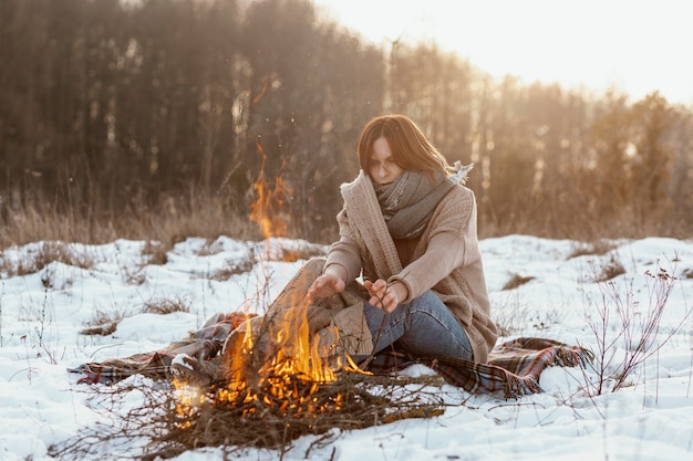 L'homme se réchauffe à côté d'un feu de camp en hiver