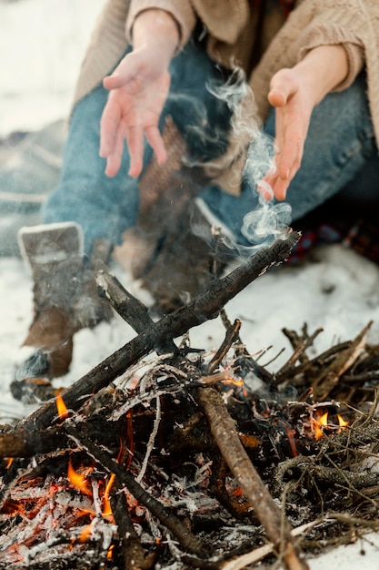 L'homme se réchauffe à côté d'un feu de camp en hiver