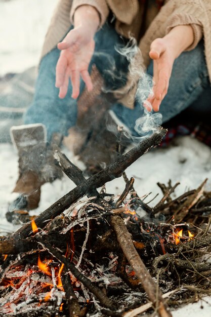 L'homme se réchauffe à côté d'un feu de camp en hiver