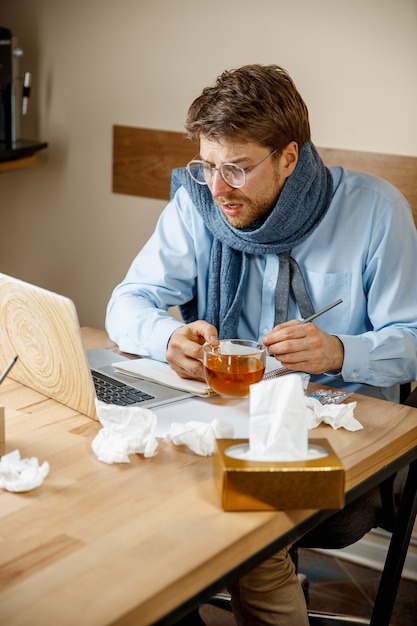 L'homme se sent malade et fatigué. homme avec tasse travaillant à la maison, homme d'affaires attrapé froid, grippe saisonnière.