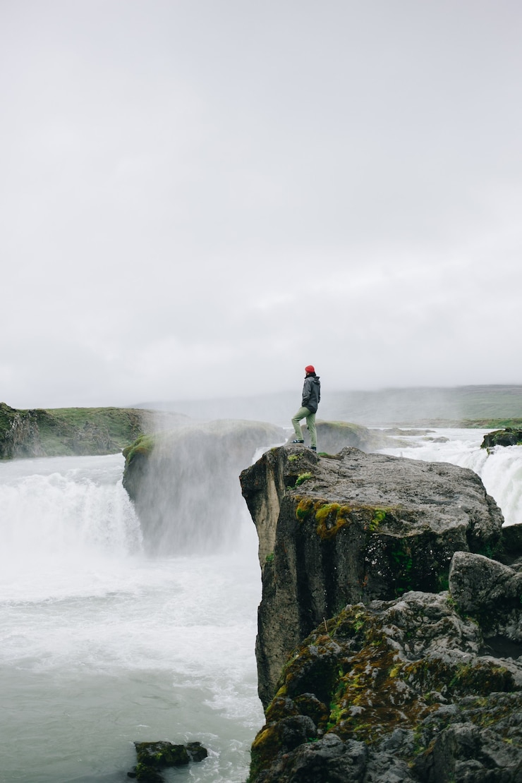 Photo gratuit l'homme se tient au-dessus de la falaise de la cascade épique