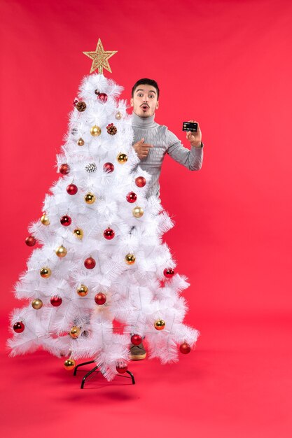 Un homme se tient à côté du sapin de Noël