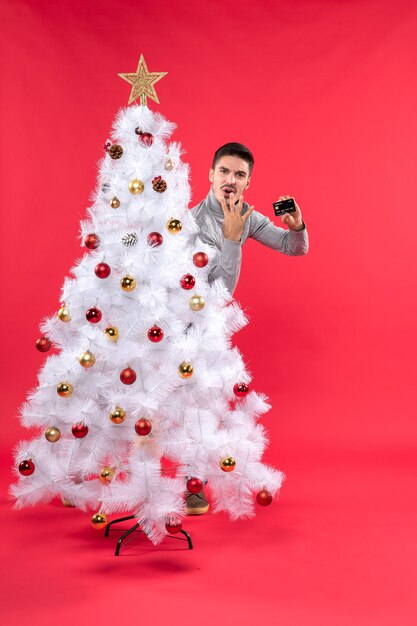 Un homme se tient à côté du sapin de Noël