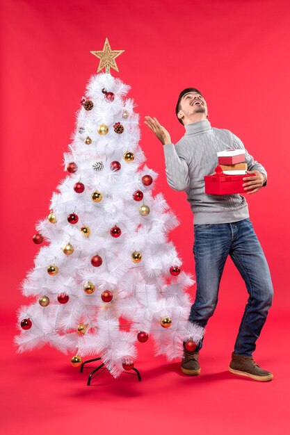 Un homme se tient à côté du sapin de Noël