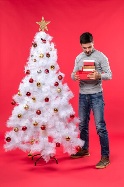 Un homme se tient à côté du sapin de Noël