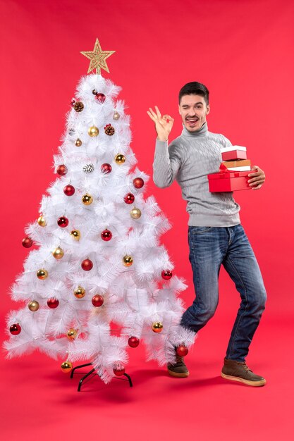 Un homme se tient à côté du sapin de Noël