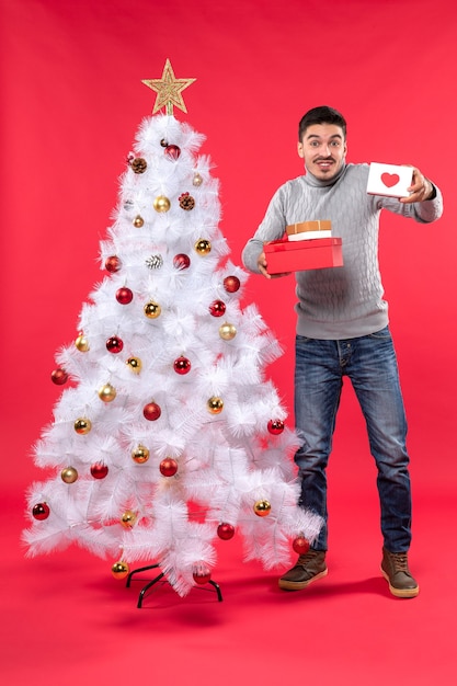 Un homme se tient à côté du sapin de Noël