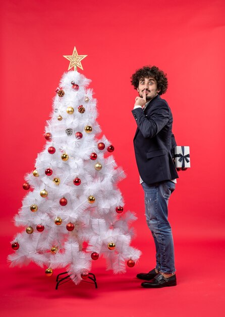 Un homme se tient à côté du sapin de Noël