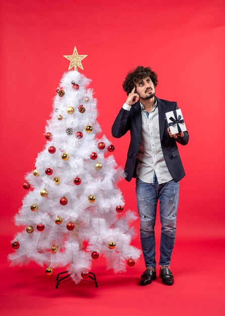 Un homme se tient à côté du sapin de Noël