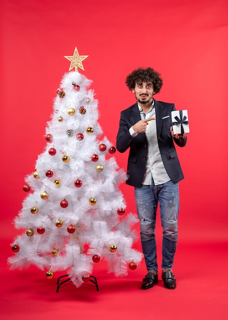 Un homme se tient à côté du sapin de Noël