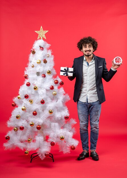 Un homme se tient à côté du sapin de Noël