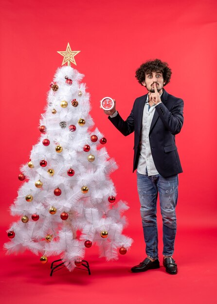 Un homme se tient à côté du sapin de Noël