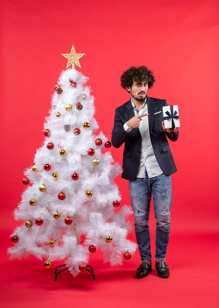 Un homme se tient à côté du sapin de Noël