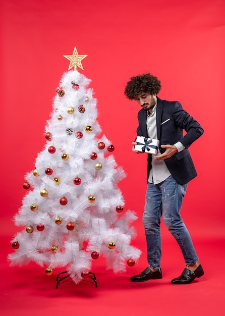 Un homme se tient à côté du sapin de Noël