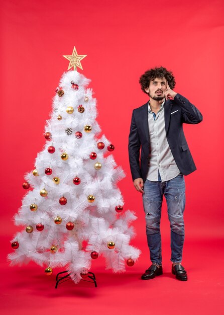 Un homme se tient à côté du sapin de Noël