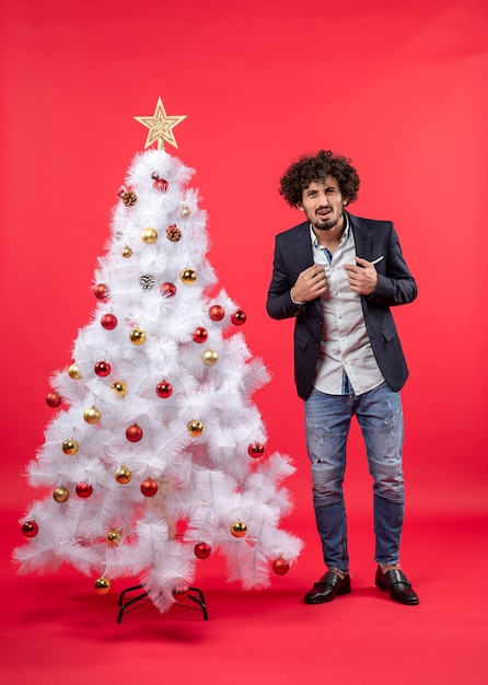 Un homme se tient à côté du sapin de Noël