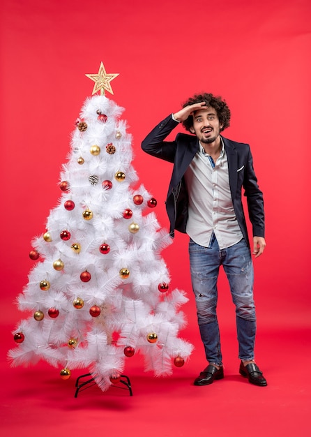 Un homme se tient à côté du sapin de Noël