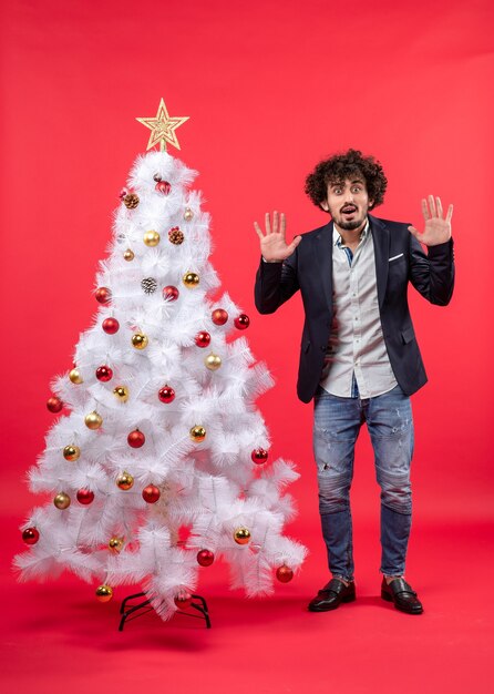 Un homme se tient à côté du sapin de Noël