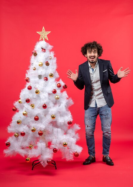 Un homme se tient à côté du sapin de Noël