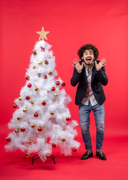 Un homme se tient à côté du sapin de Noël