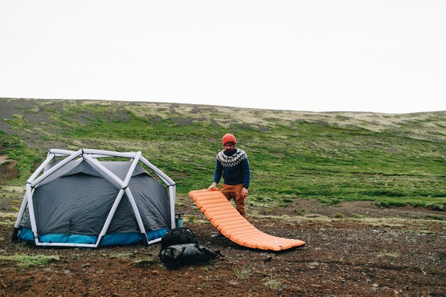 L'homme se tient à côté d'une tente moderne en Islande