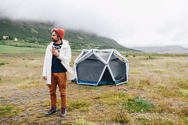 L'homme se tient à côté d'une tente moderne en Islande