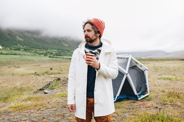 L'homme se tient à côté d'une tente moderne en Islande