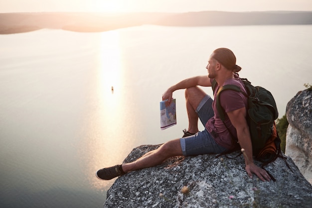 Photo gratuite homme séduisant appréciant la vue sur le paysage de montagnes au-dessus de la surface de l'eau.