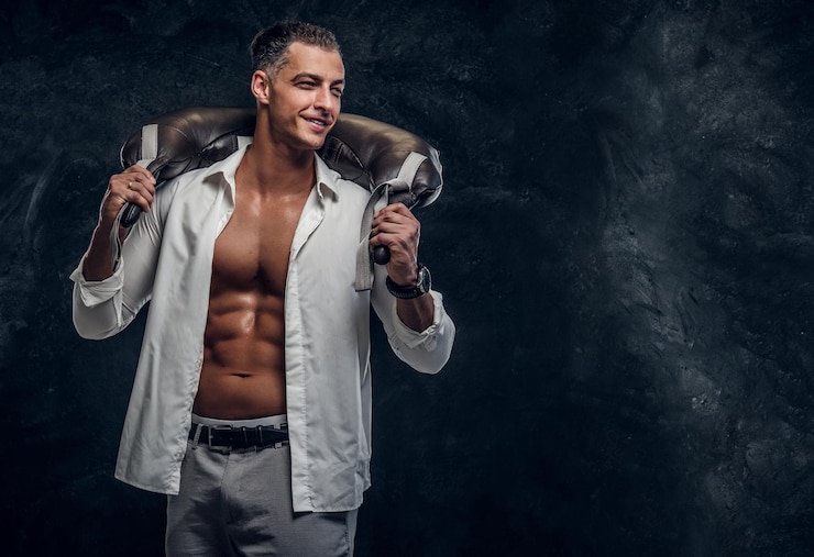 Photo gratuit un homme séduisant en chemise ouverte blanche et avec un sac de poids sur ses épaules pose pour le photographe.